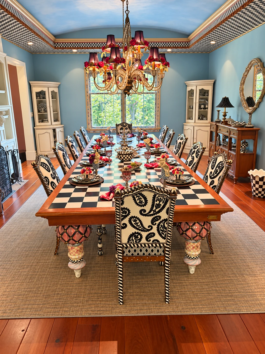 An elaborately set long dining table in a private home, with patterned chairs and a chandelier